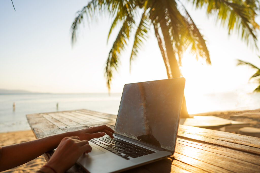 girl freelancer working on the sea at sunset with a computer